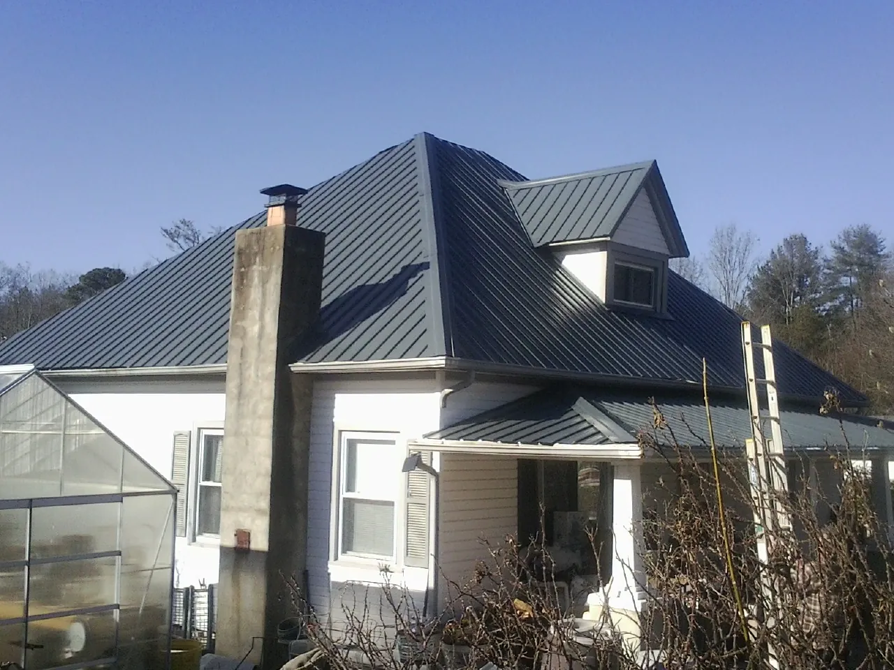 Dark blue standing seam metal roof on a white farmhouse with dormer — Slate & Tile Roof Repair by Roofing Brothers in Berlin Center