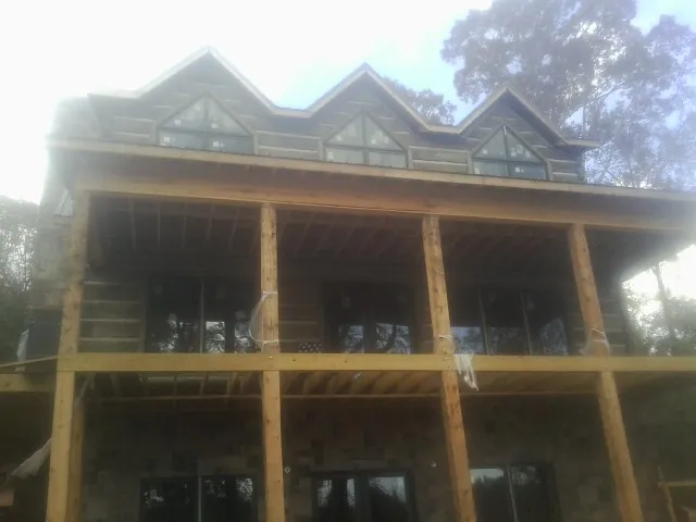 Dormers and porch framing on a large log home under construction — Roof Coating work by our crew in Berlin Center