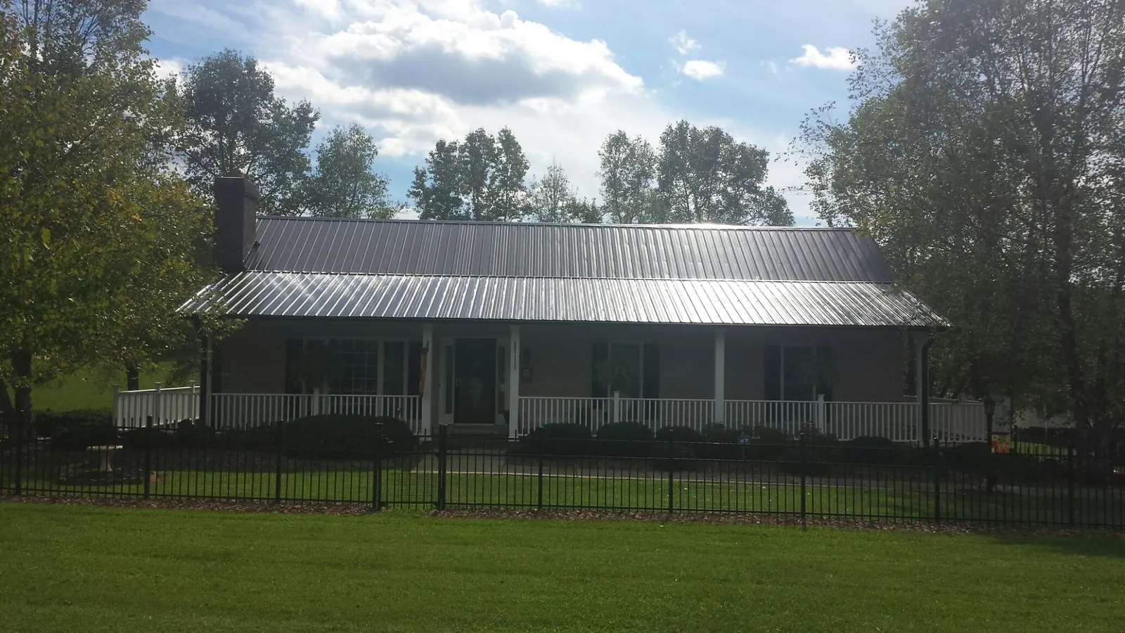 Gray metal roof on a brick ranch with a full width front porch — Gutter Guard Installation work by our crew in Berlin Center