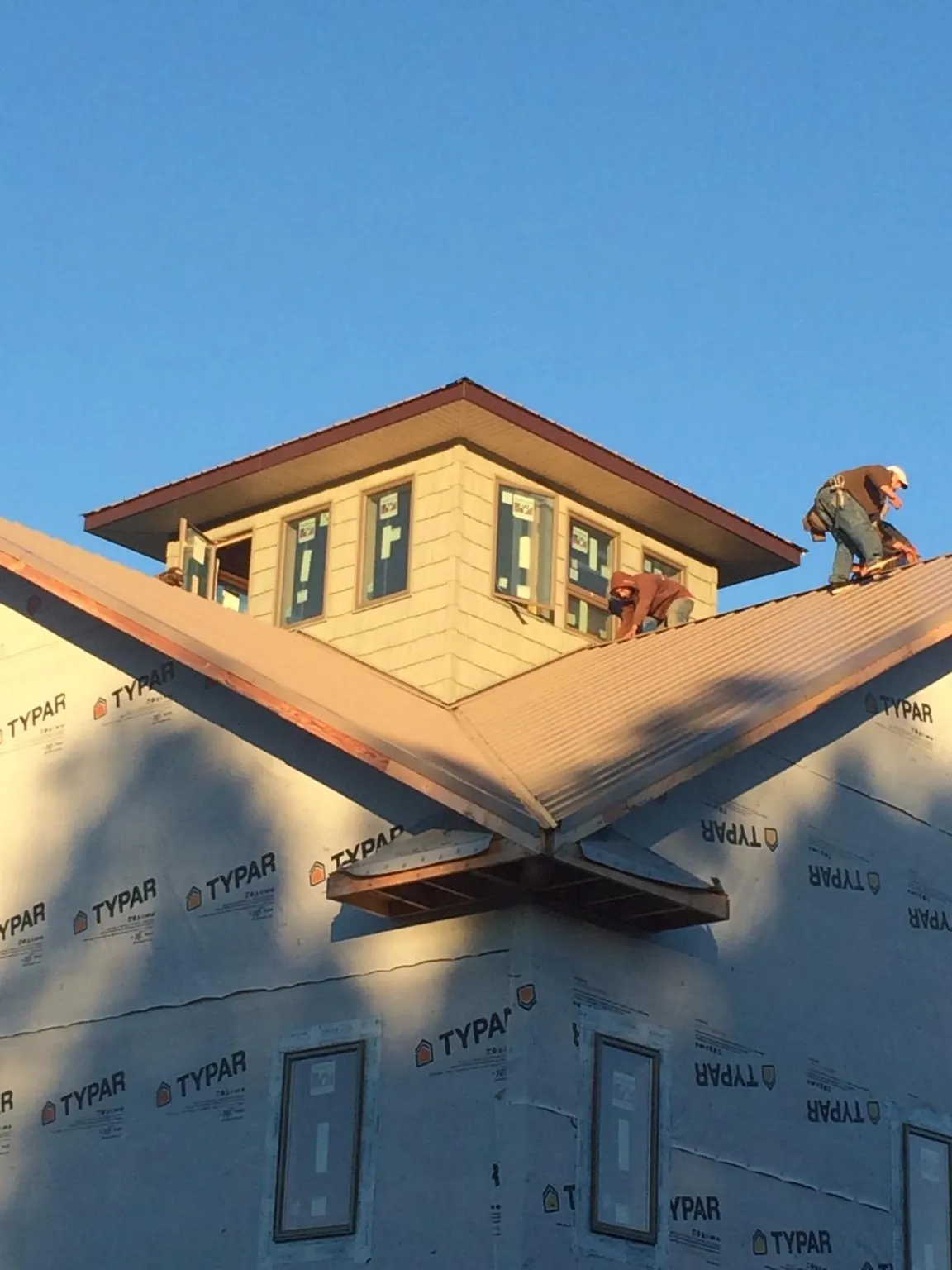 Roofers working around a rooftop cupola on a new metal roof at sunset — Roof Waterproofing in Berlin Center by Roofing Brothers